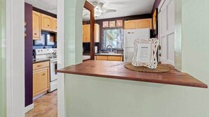 A kitchen with wooden cabinets, a white refrigerator, and a wooden countertop. - Lincolnville Cottage | Sunroom & Fenced Yard (St. Augustine)