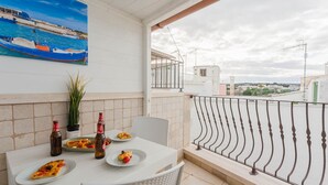 A balcony with a white table set for two, two bottles of beer, and plates with pizza slices.