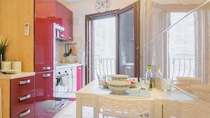 A modern kitchen with a red cabinet, a dining table with chairs, and a small cart.
