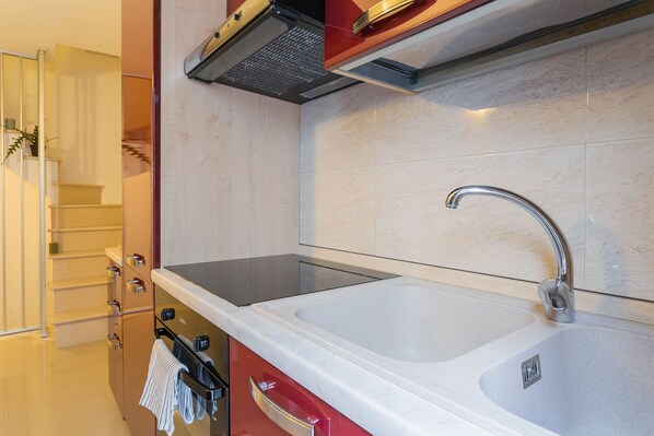 A modern kitchen with a double sink, stainless steel faucet, and a built-in range hood. - Polly House by Wonderful Italy (Polignano a Mare)