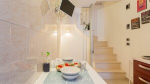 A kitchen with a white countertop, a bowl, a glass, and a bottle.