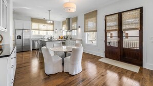 A modern kitchen with a central island, white cabinetry, and a dining area with a round table and chairs.