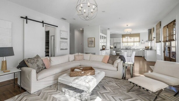 A modern living room with a sectional sofa, a coffee table, and a dining area in the background.
