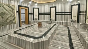 A modern hotel lobby with a central marble fountain, striped wallpaper, and a geometric ceiling design. - S Class Hotel Convention Center (Gaziantep)
