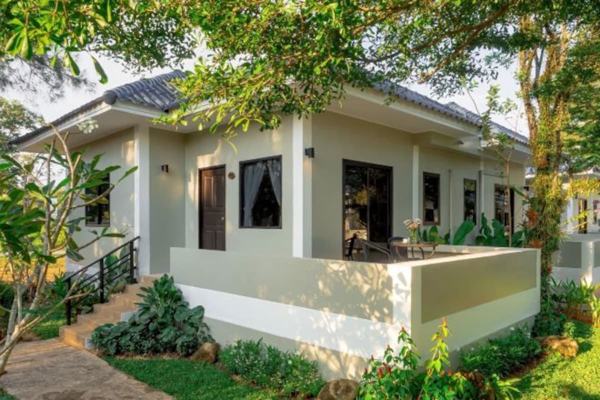 A modern house with a flat roof, a covered porch, and a stone staircase leading to the entrance.