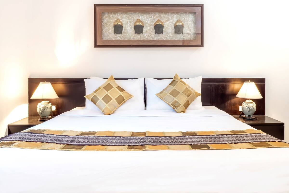 A hotel room with a bed, two nightstands, two lamps, and a framed artwork above the bed.