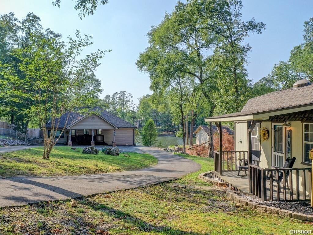 A residential property with a covered porch, a pathway leading to a garage, and a lake in the background.