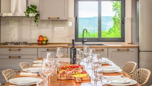 Una cucina moderna con zona pranzo apparecchiata per un pasto, con un'ampia finestra vista su spazi verdi.