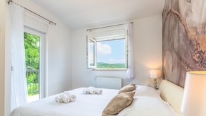 Una camera da letto con un letto grande, una finestra con vista su spazi verdi e un termosifone.