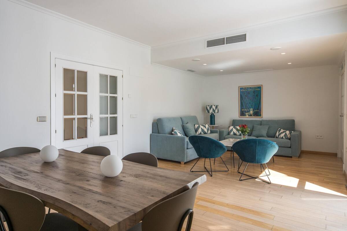 A modern living room with a wooden dining table, two sofas, and a coffee table.
