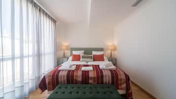 A neatly made bed with a striped bedspread, pillows, and two bedside lamps.
