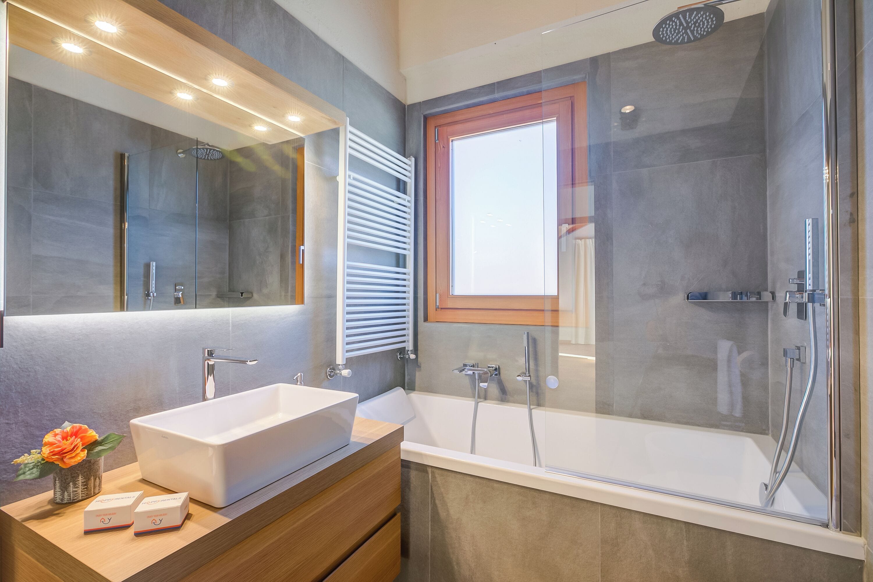 A modern bathroom with a large mirror, a rectangular sink, a bathtub, and a glass-enclosed shower.