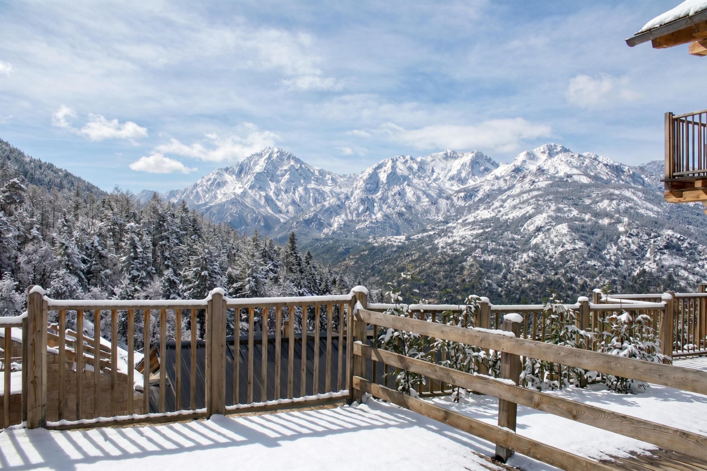 A wooden balcony with a view of snow-covered mountains.