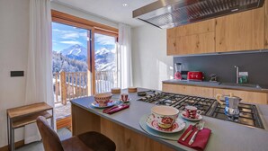 Una cucina moderna con piano cottura a gas, mobili in legno e vista sulle montagne attraverso la finestra.