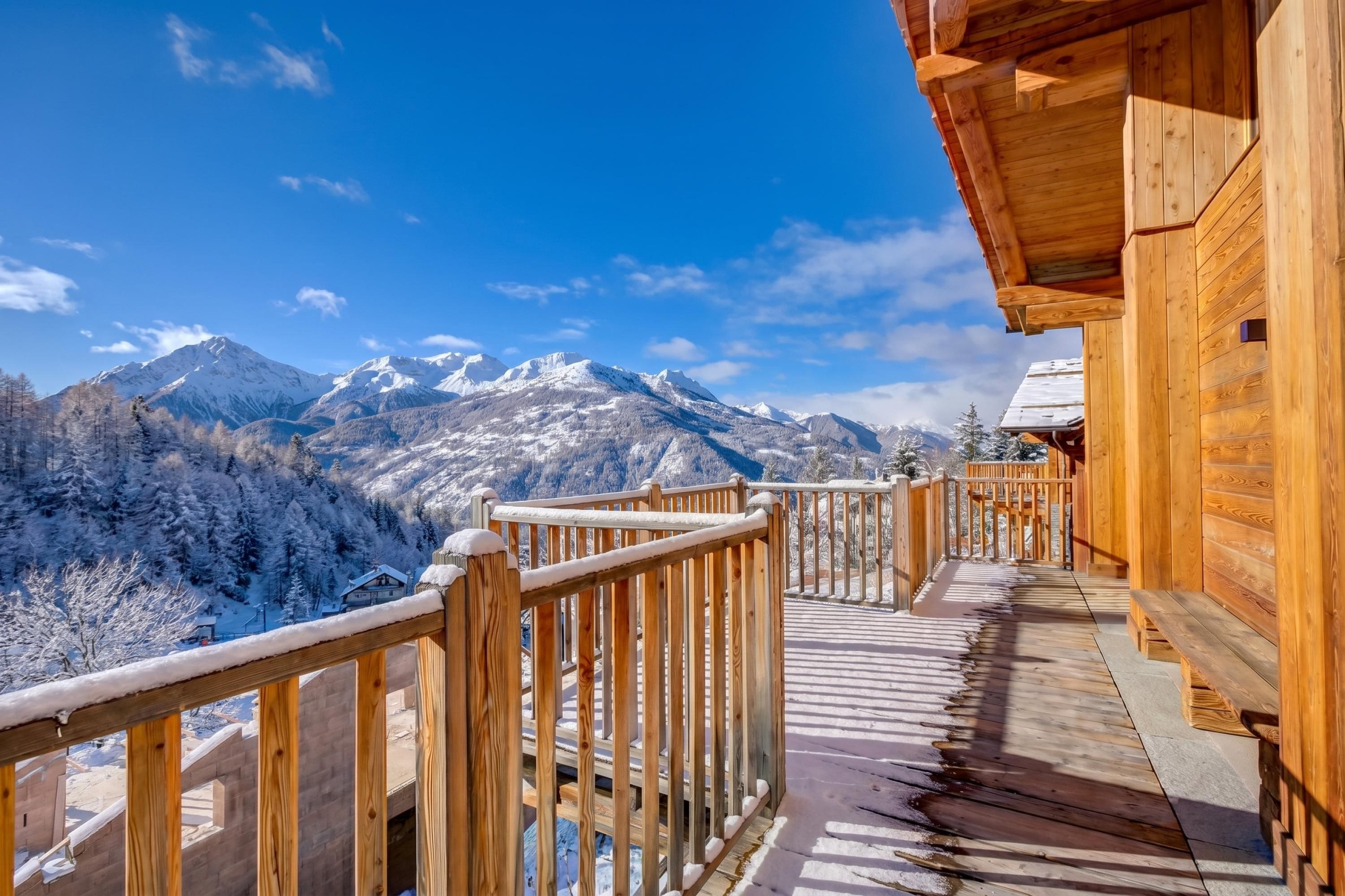 Un balcón de madera con vistas a montañas nevadas.