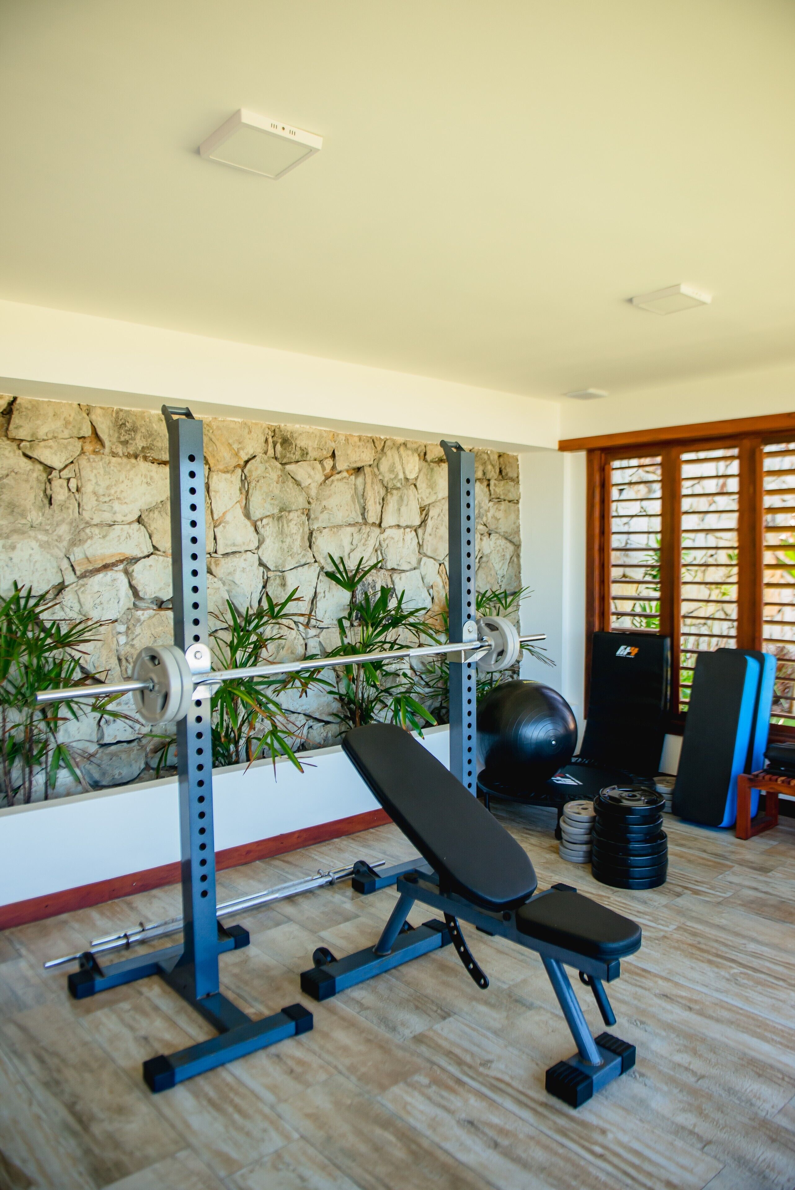 Un gimnasio con pared de piedra, equipamiento de levantamiento de pesas y un banco.