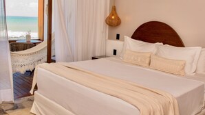 A bedroom with a large bed, a view of the beach, and a ceiling light fixture. - Carlore Hotel Taíba (São Gonçalo do Amarante)