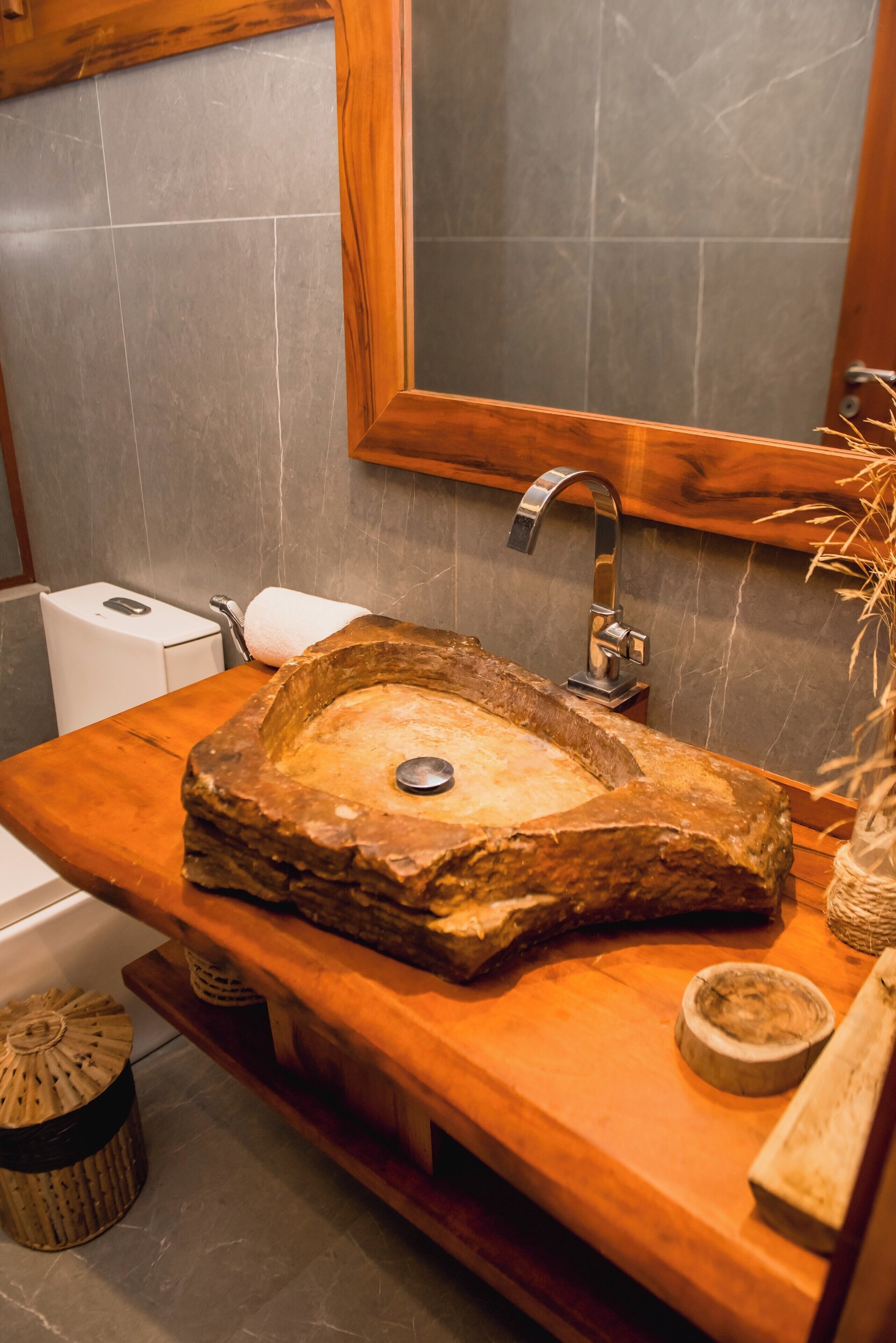Un baño con un lavamanos de piedra, encimera de madera y un espejo.