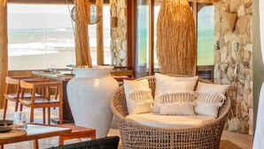 A dining area with wicker furniture, a large vase, and a view of the ocean. - Carlore Hotel Taíba (São Gonçalo do Amarante)
