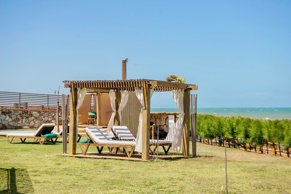 Eine Strandkabine mit Steinwand, Holzpergola und Blick auf den Ozean.