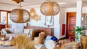 A spacious living area with a long wooden table, wicker furniture, and hanging rattan chandeliers. - Carlore Hotel Taíba (São Gonçalo do Amarante)