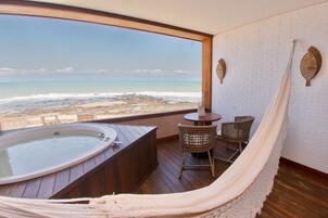 Un balcón con hidromasaje, sillas de mimbre y una hamaca con vista a la playa.