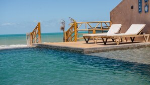 A poolside area with two sun loungers, a wooden deck, and a view of the ocean. - Carlore Hotel Taíba (São Gonçalo do Amarante)