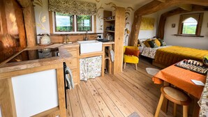 L’intérieur d’un chalet rustique comprenant une cuisine, un coin repas et un lit.