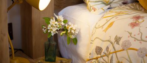 A bedside table with a lamp, a book, and a vase with flowers.