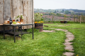 A rustic outdoor setting with a table set for a meal, a beer bottle, and a potted plant. - Luxury Shepherd's Hut Style Cabin With Views (Hereford)