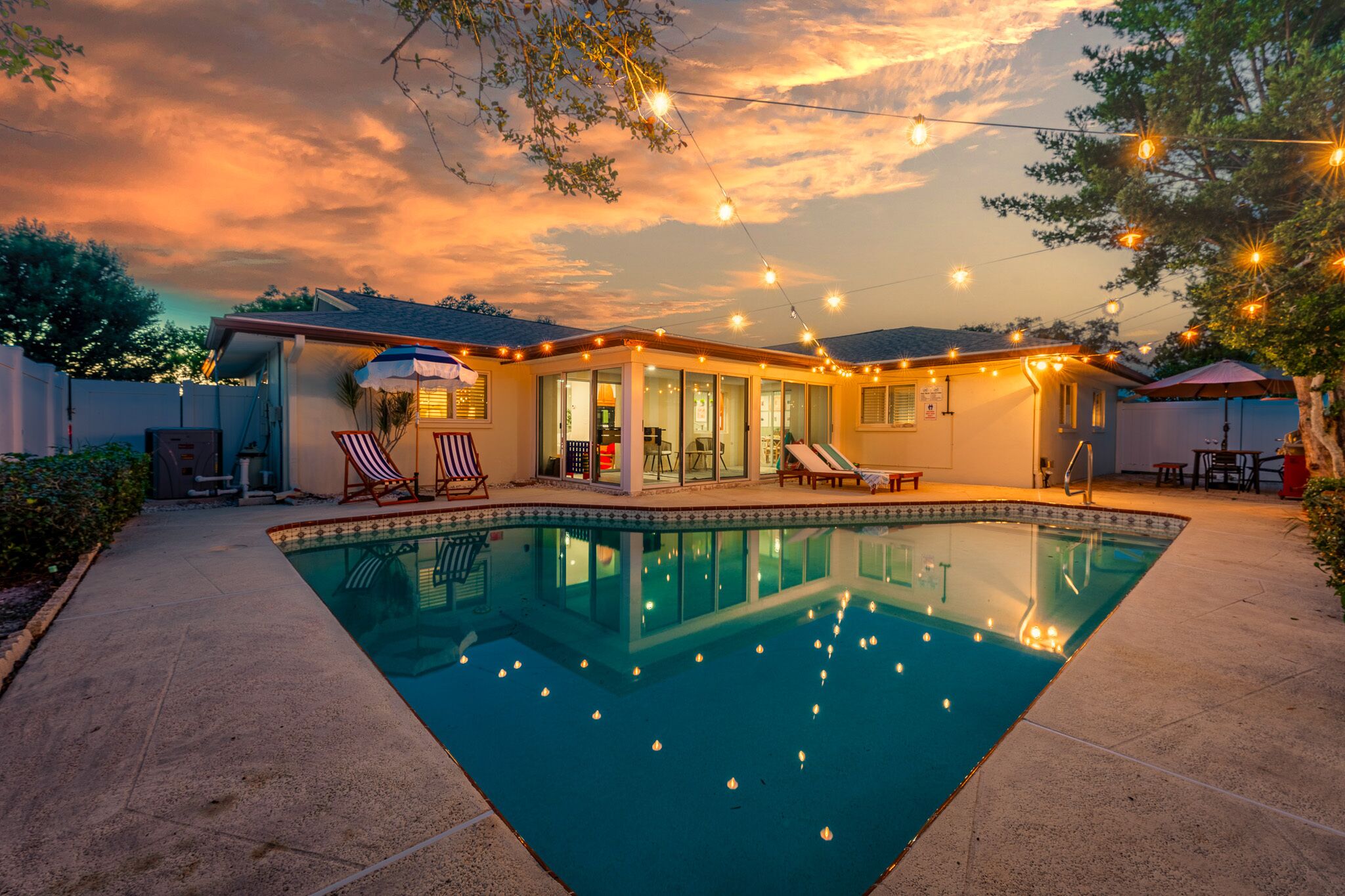 Un jardin avec une piscine, des guirlandes lumineuses et du mobilier d’extérieur.