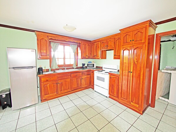 A kitchen with wooden cabinets, a refrigerator, a stove, and a microwave.