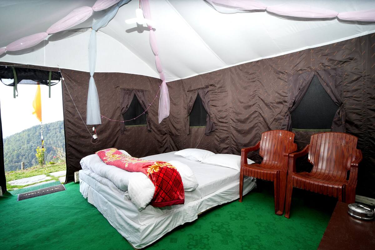A tented room with a bed, a chair, and a view of the outdoors.