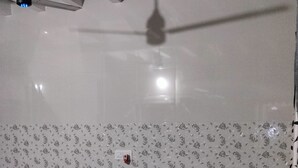Un dormitorio con cama, ventilador de techo, pared con diseño y suelo de piedra.