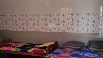 Quarto com duas camas, uma de casal e uma individual, com papel de parede estampado com motivos florais.