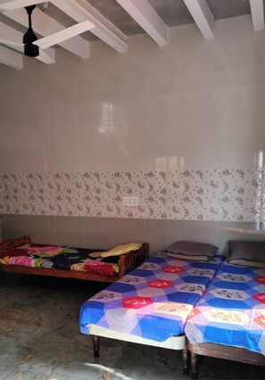 A room with two beds, one double and one single, with floral-patterned wallpaper.