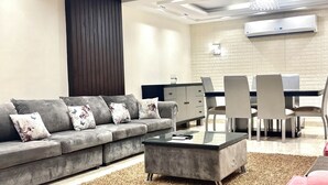 A modern living room with a grey sofa, a glass coffee table, and a dining area with chairs and a table. - Block B - 401 (Agouza)