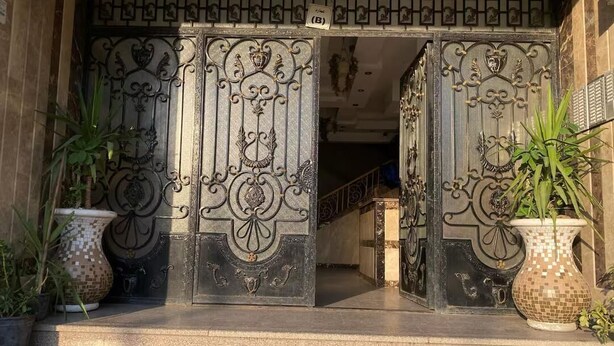 A set of ornate metal gates with intricate designs, leading to a building entrance. - Block B - 401 (Agouza)