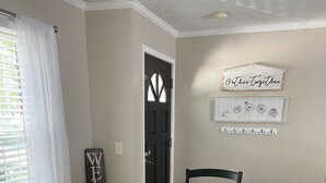 Une salle à manger avec une table en bois, des chaises noires, une lanterne décorative et une pancarte « Bienvenue ».