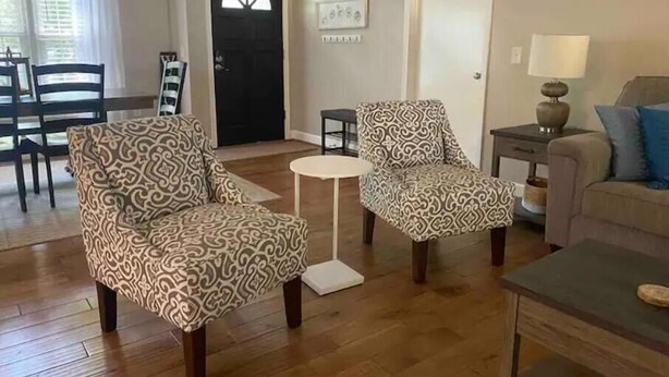 Un salon avec des fauteuils à motifs, une petite table ronde et un canapé.