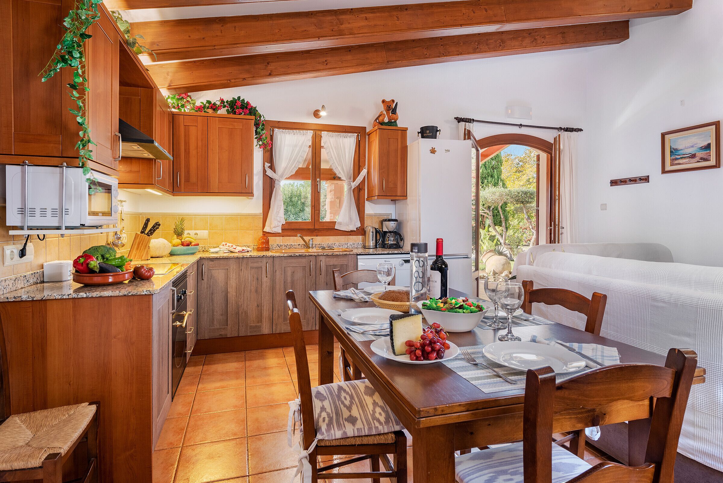 A wooden kitchen with a dining area, featuring a table set for two with plates, glasses, and a bottle of wine.