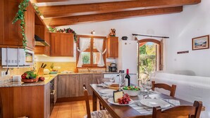A wooden kitchen with a dining area, featuring a table set for two with plates, glasses, and a bottle of wine.