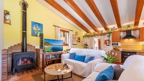A cozy living room with a fireplace, a sofa set, a coffee table with chess pieces, and a TV.
