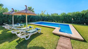 A swimming pool with lounge chairs and a thatched umbrella.