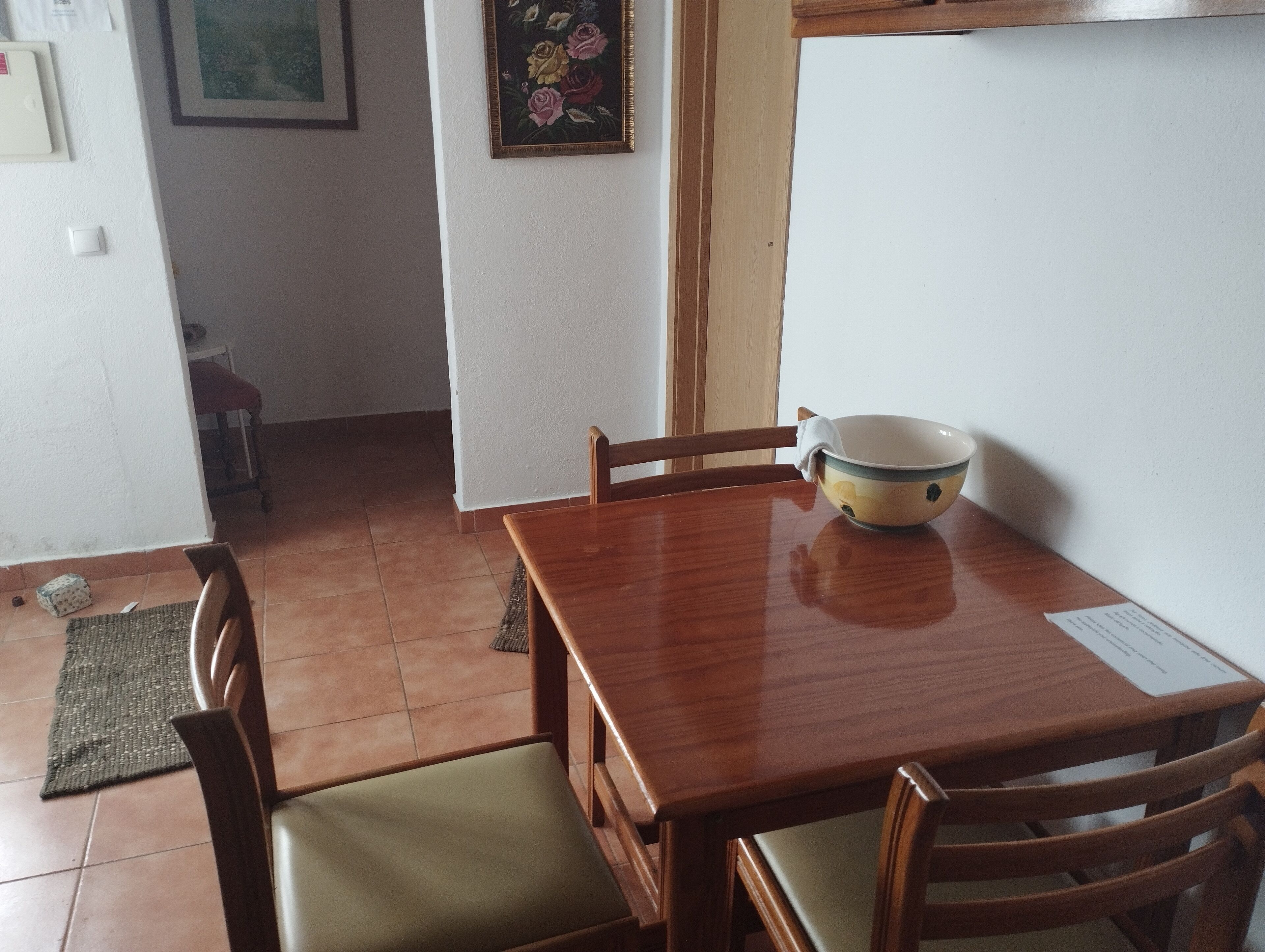 A wooden dining table with a bowl and a menu on it, surrounded by chairs.