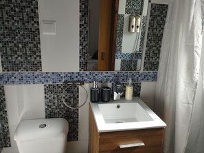 Bathroom features a sink, toilet, and shower area with mosaic tile walls.