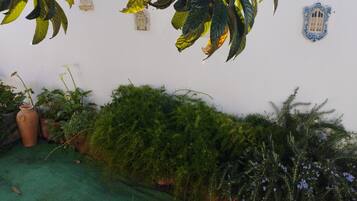 A garden area with various potted plants and a green artificial turf.
