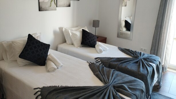 Une chambre d’hôtel avec deux lits, un miroir et trois tableaux représentant des motifs floraux accrochés au mur.