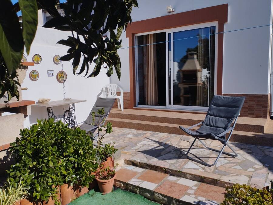 Une terrasse avec une table, deux chaises et des plantes en pot.