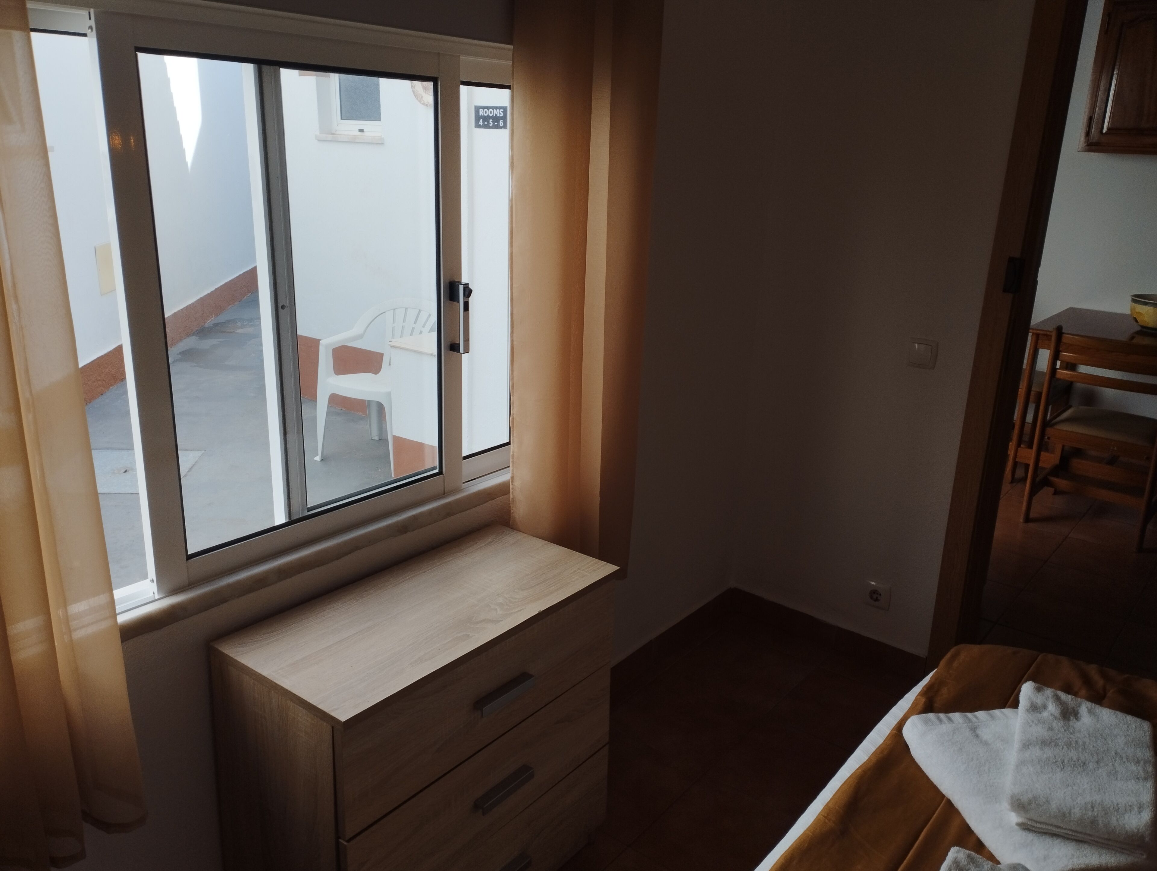 Una habitación con ventana, un escritorio de madera y una silla.